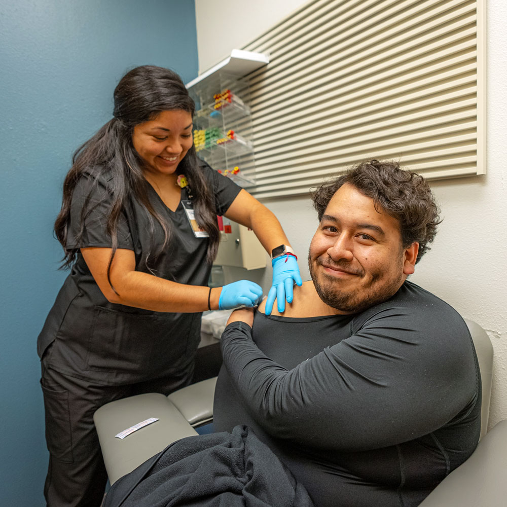 COVID 19 Services_Male patients receives a COVID-19 vaccine from a female lab technician.