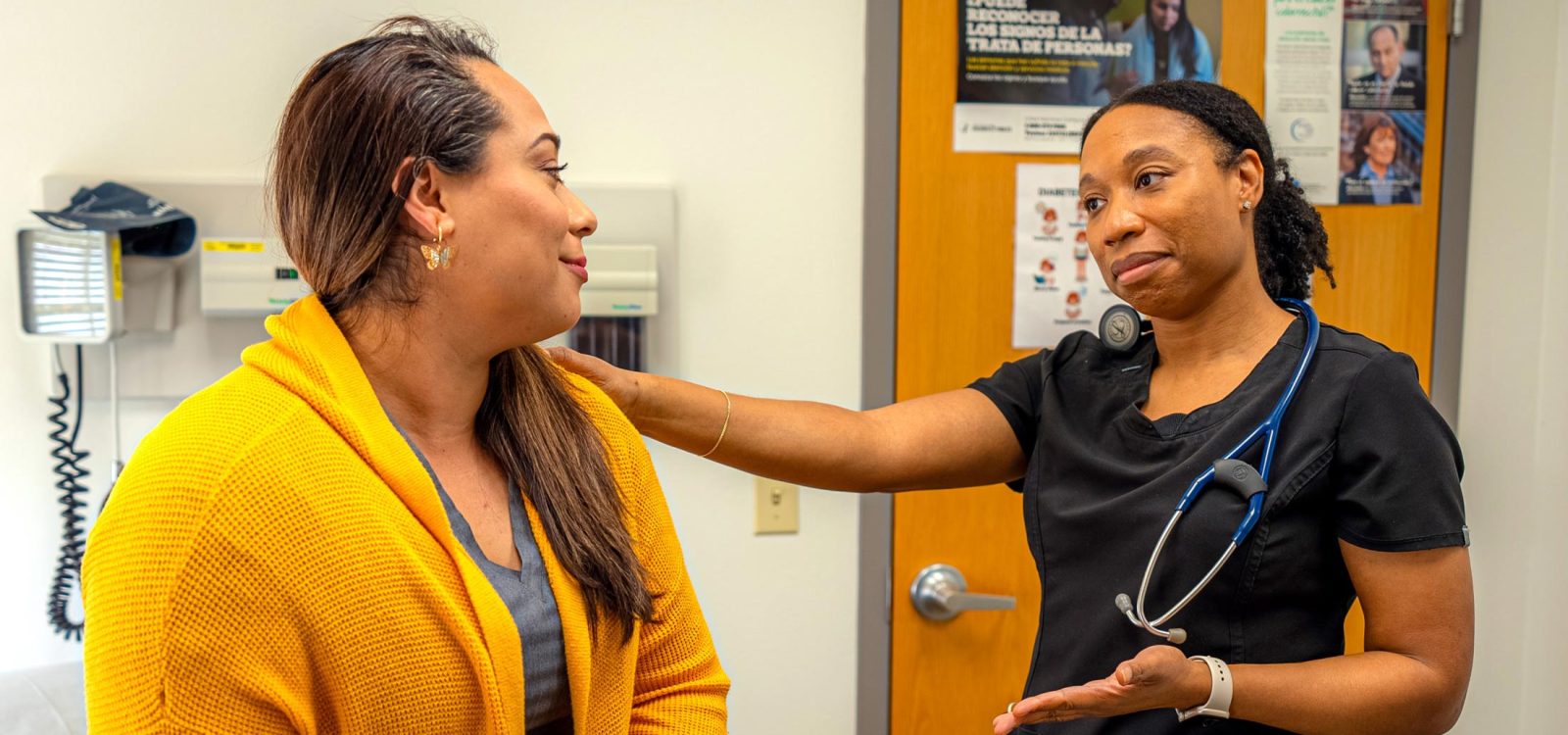 CHCSCT Careers_Current Openings_Medical Assistant. A female Medical Assistant visits with a female patient and has her hand on her shoulder.