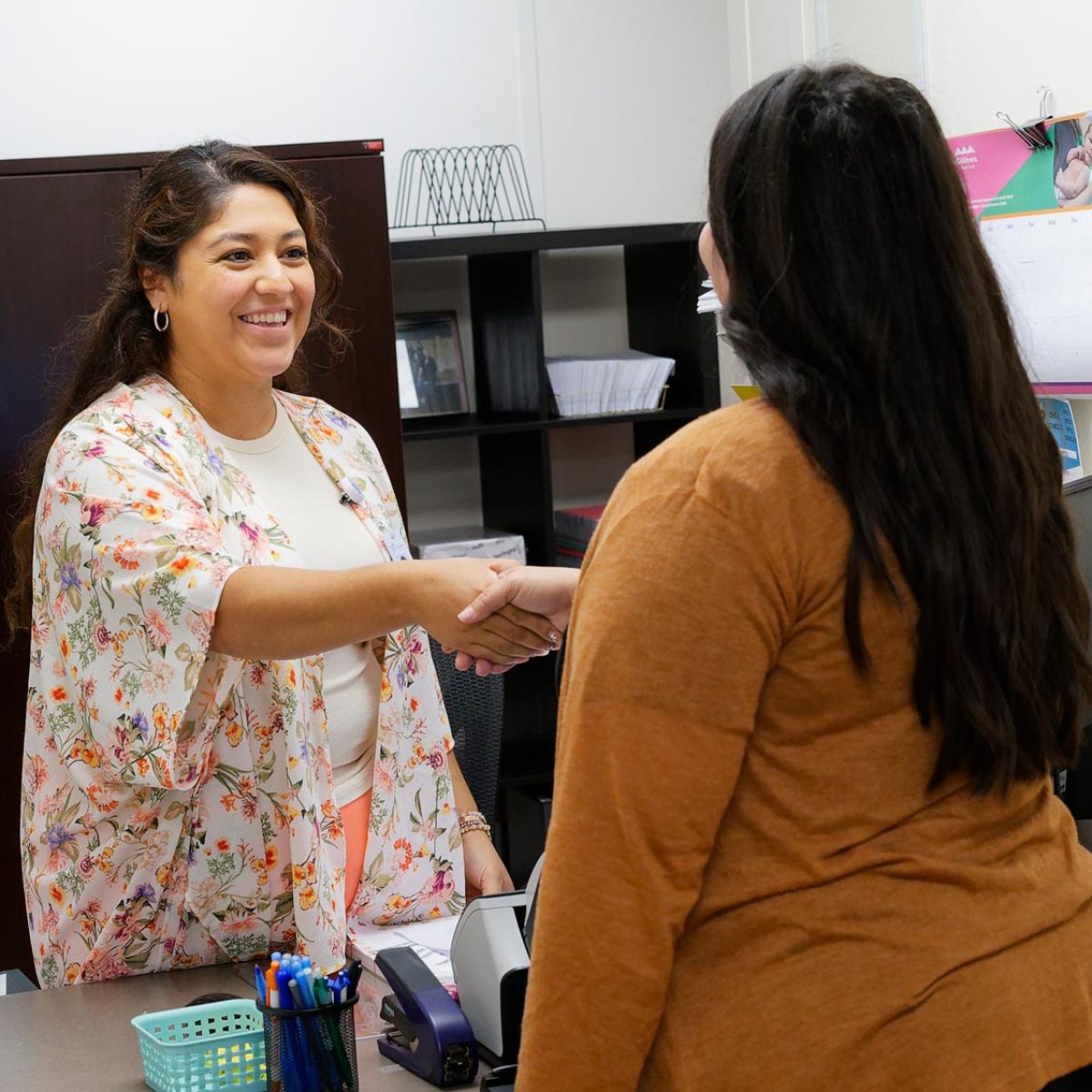 A woman shakes hands with a customer service representative as she arrives to the health center.
