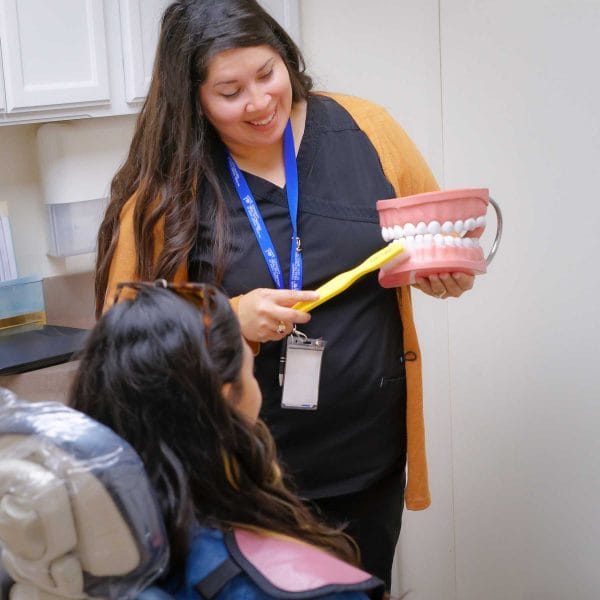 dental services - dentist demonstrating dental cleaning to patient at Community Health Centers of South Central Texas